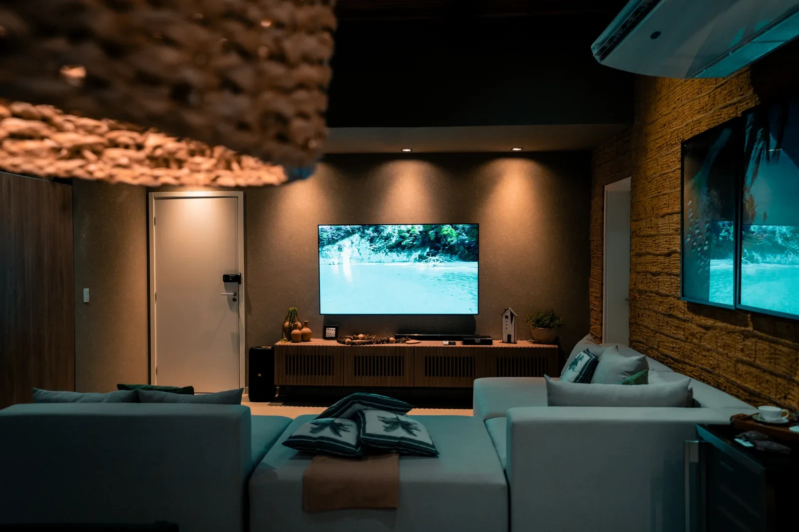 Sofá da sala com TV de 75 polegadas, ao anoitecer.